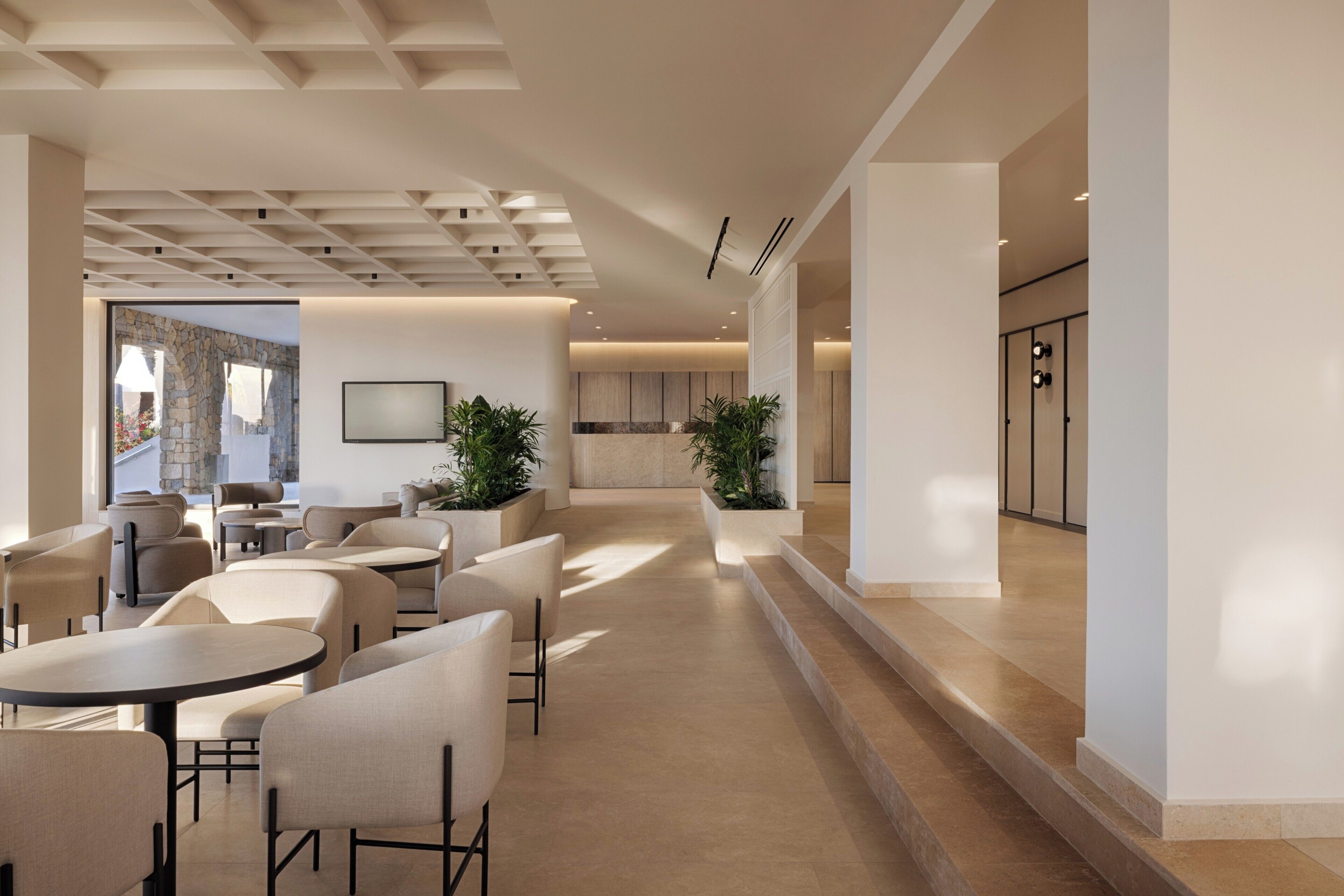 A modern interior with a seating area, a kitchen in the background, and a staircase leading to an upper level.