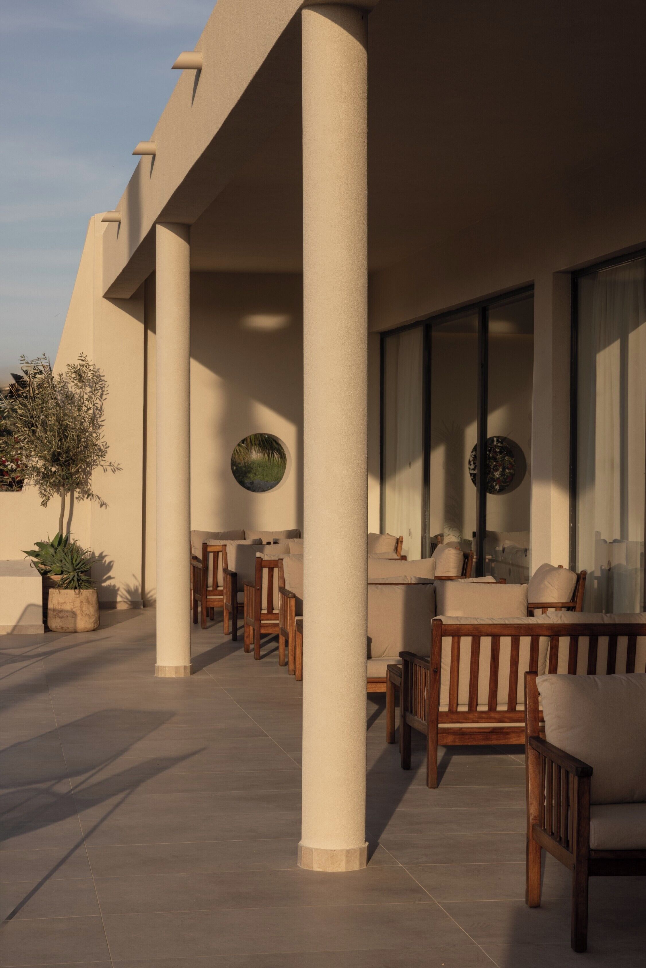 A covered outdoor seating area with wooden furniture and potted plants.