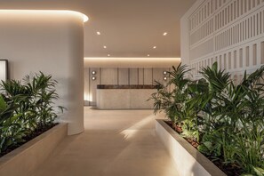 Un espace d’accueil moderne avec un mur incurvé, un comptoir d’accueil et des plantes en pot.