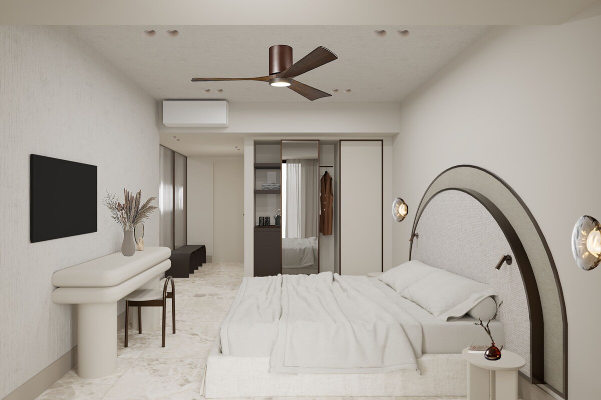 A modern bedroom with a bed, bedside table, and a desk area.