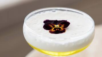 Un cocktail servi dans un verre à pied, décoré d’une fleur.