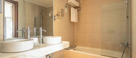 A modern bathroom with two sinks, a large mirror, a glass-enclosed shower, and a towel rack.