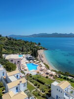 Un resort con piscina, playa y vistas a la montaña.