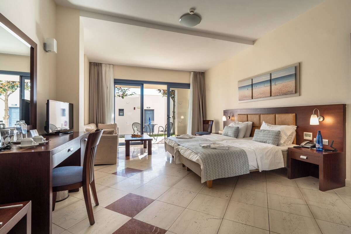 A hotel room with a bed, desk, chair, and a view of the outside.