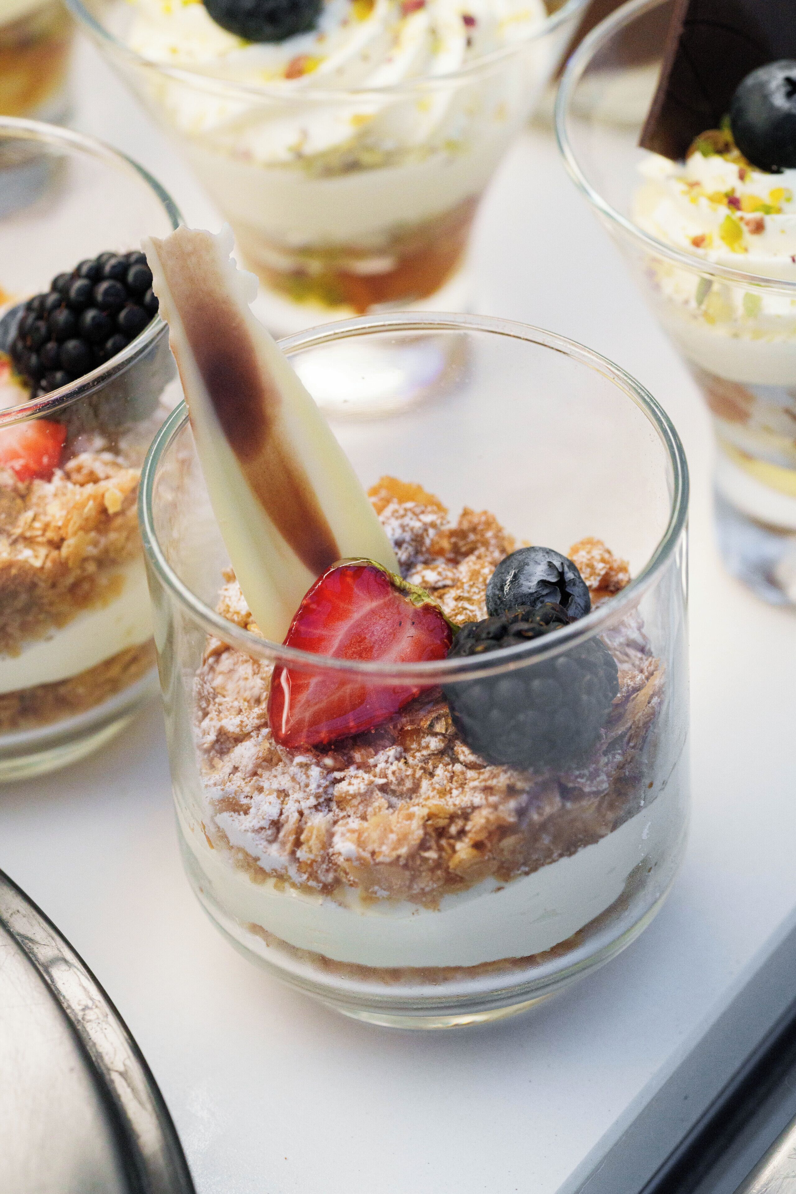 A dessert with layers of cream and fruit, served in a clear glass.