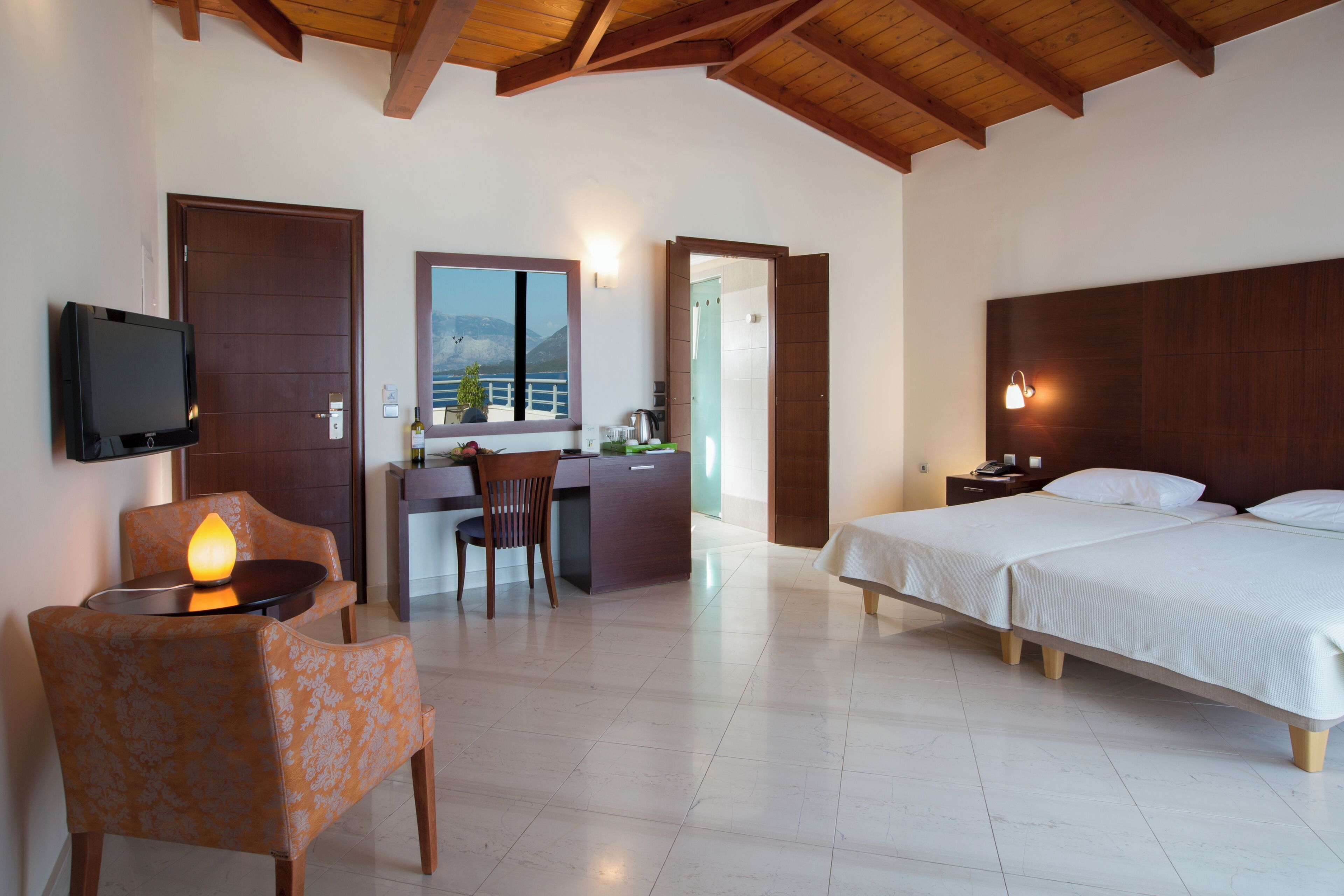 Une chambre d’hôtel avec un lit, un bureau et une chaise, une télévision et une vue sur les montagnes.