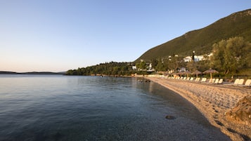 Enjoy a serene beach experience with a clear view of the shoreline, lined with umbrellas and lounge chairs.