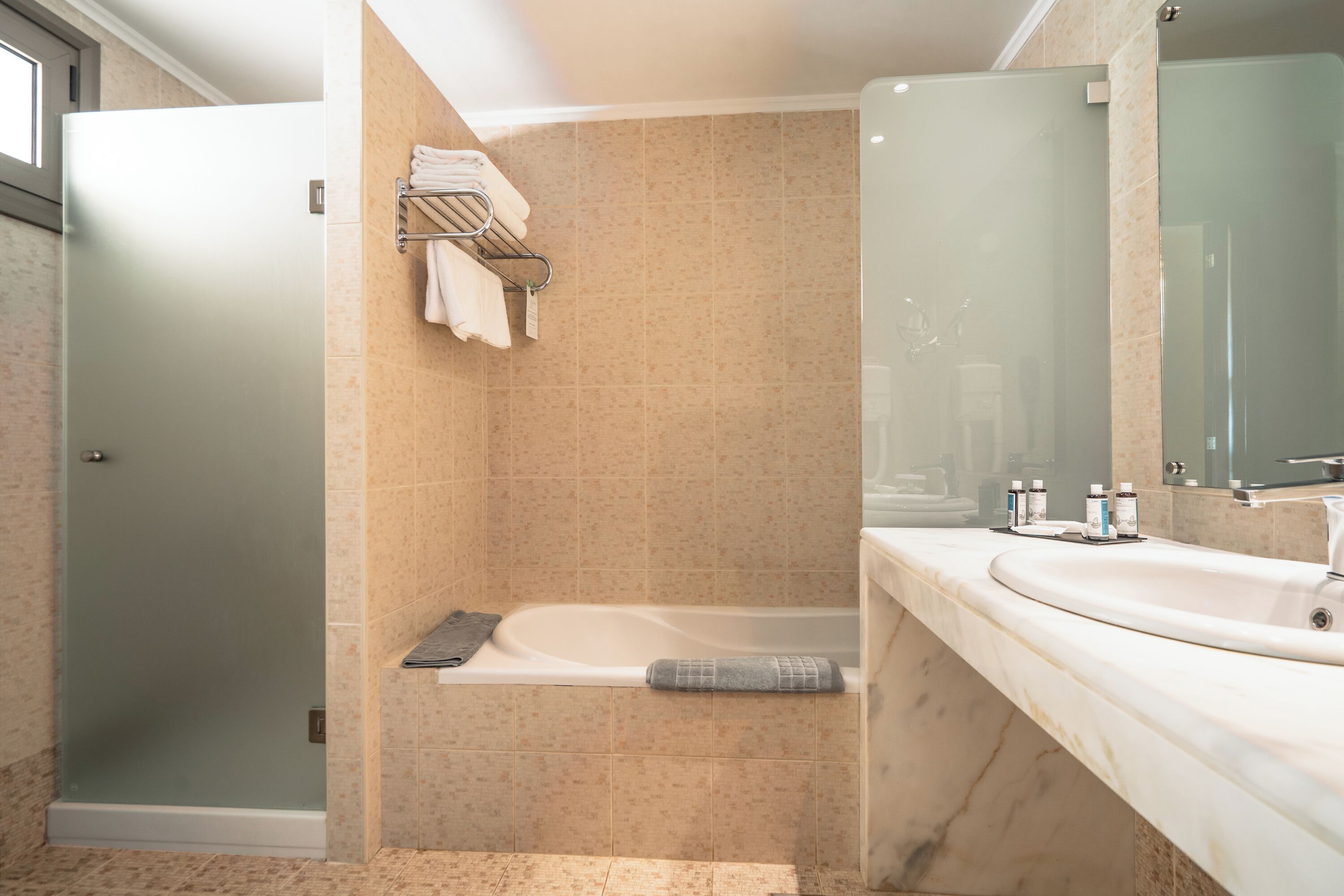A modern bathroom with a glass-enclosed shower, a bathtub, and a vanity with a large mirror.