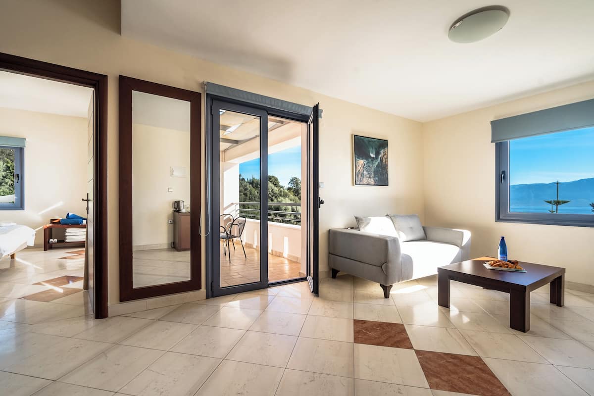 A spacious living area with a sliding glass door leading to a balcony, a sofa, a coffee table, and a view of the outdoors.