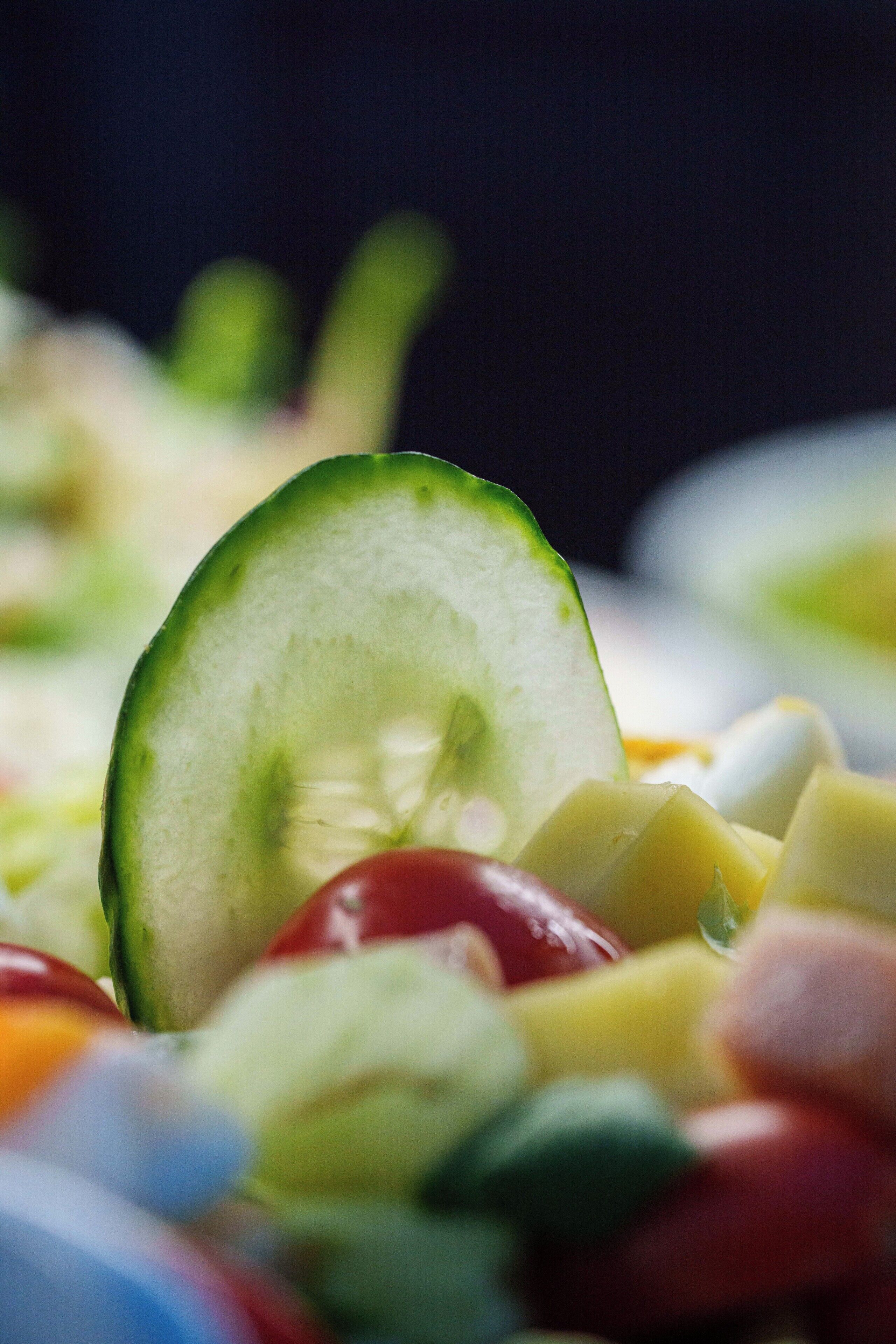 Une vue rapprochée d’une salade de fruits composée de différents fruits et d’une tranche de concombre.