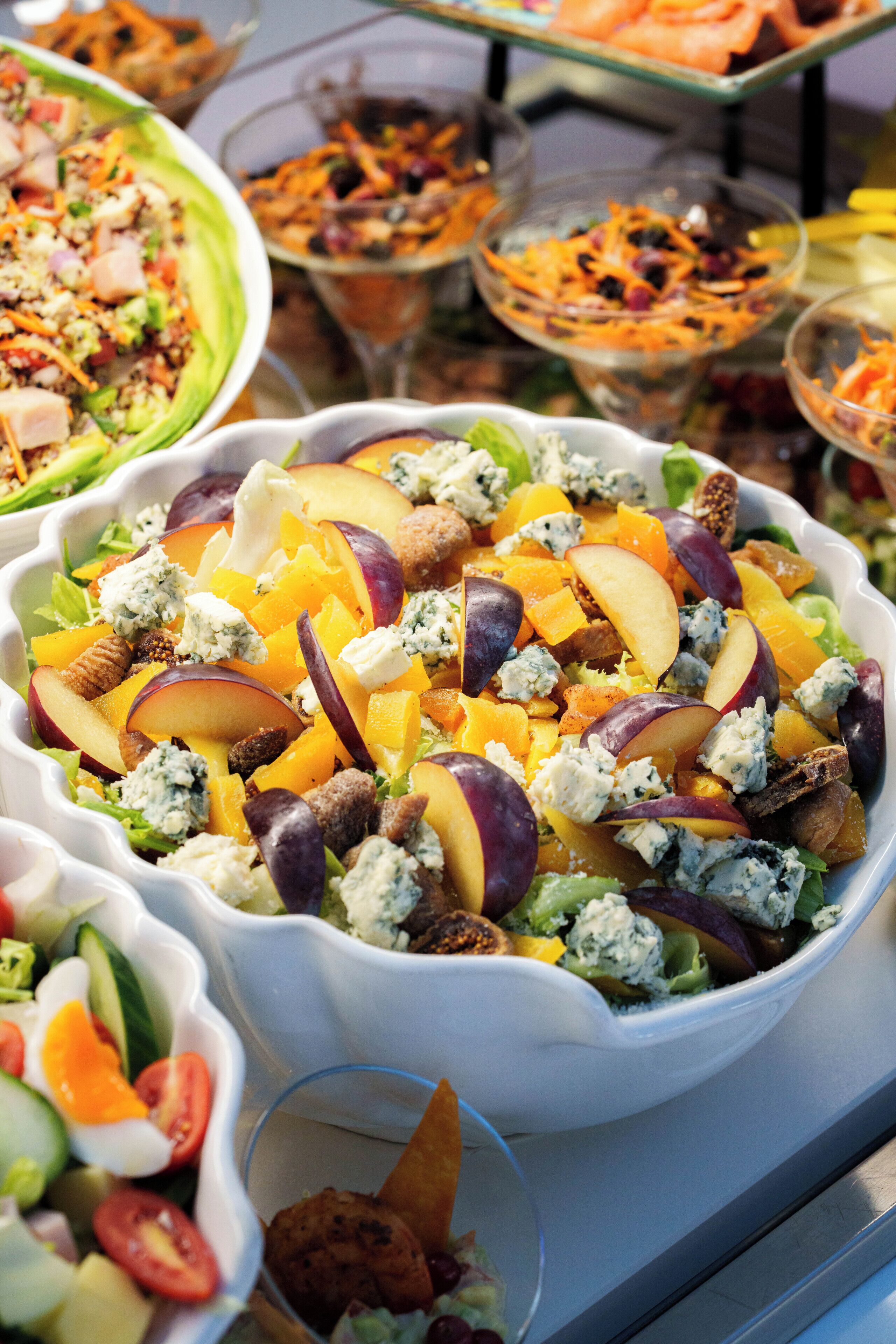 A variety of food dishes in bowls, including a salad with fruits and cheese.