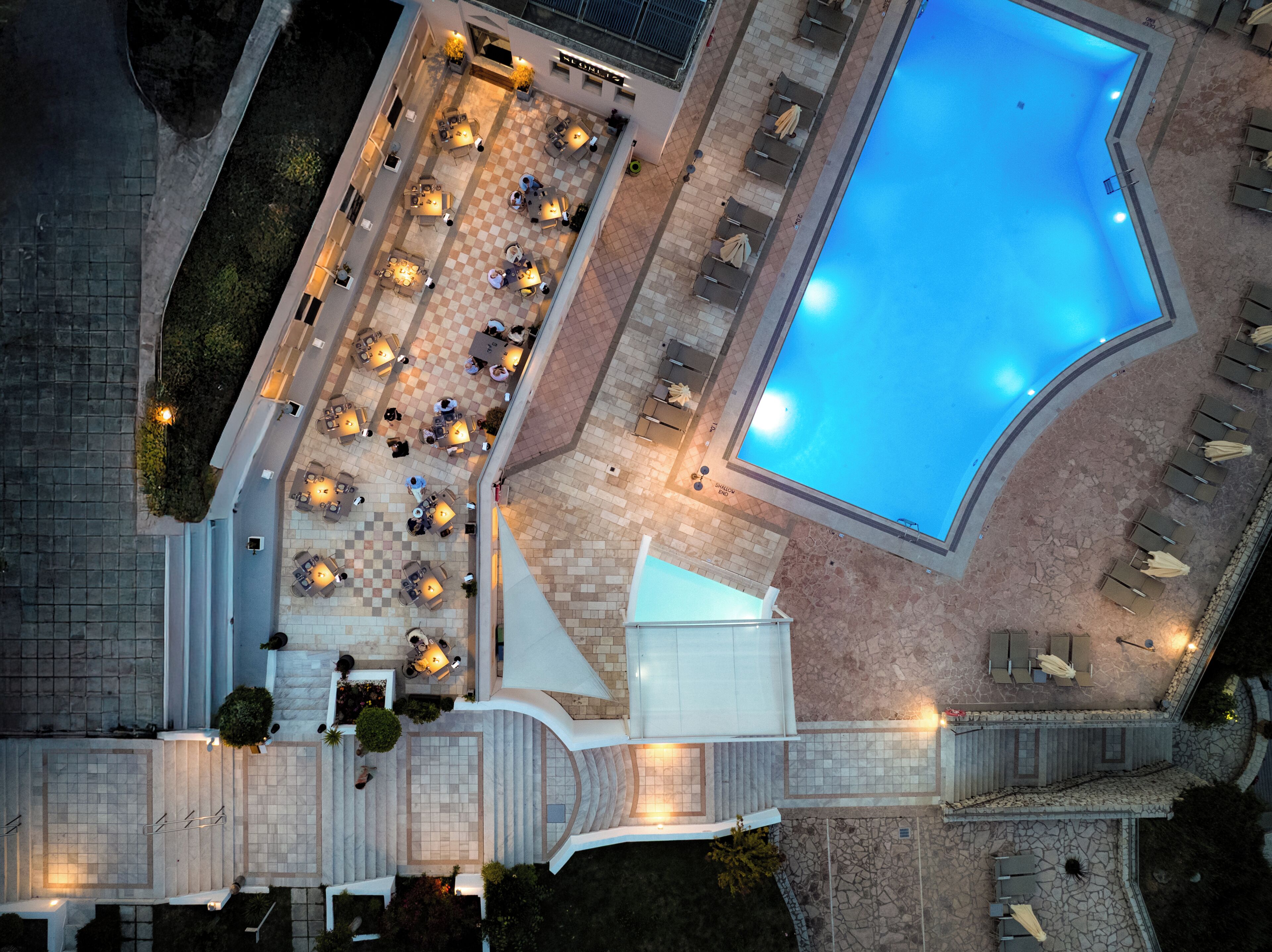 Vue aérienne d’un hôtel doté d’une piscine, d’un espace extérieur aménagé et d’une terrasse couverte.