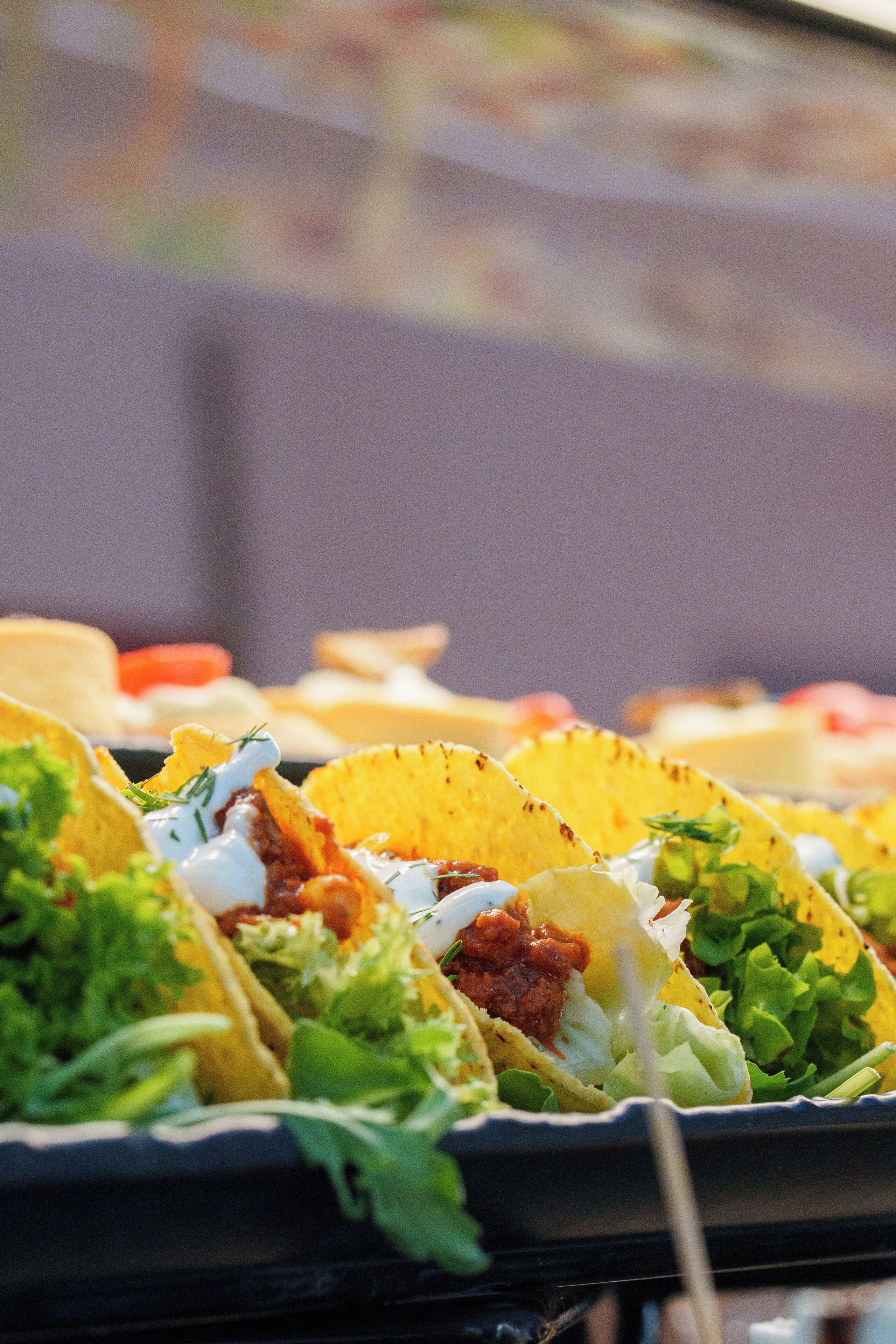 A tray of tacos with various toppings and sauces.