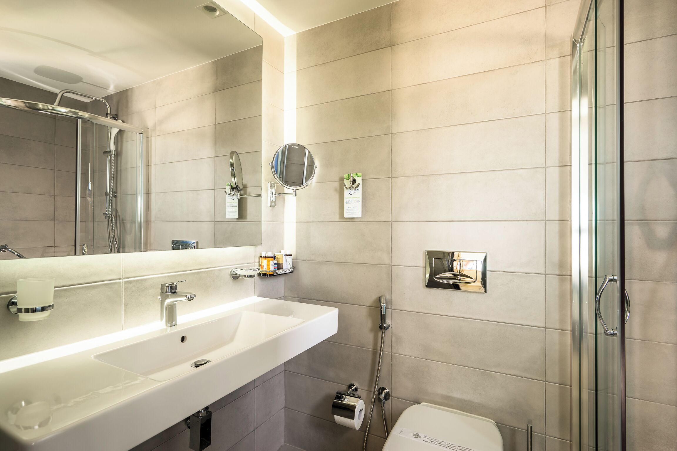A modern bathroom with a large sink, mirror, and glass shower enclosure.