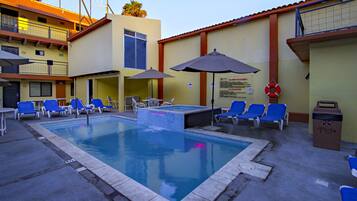 Een buitenzwembad, parasols bij het zwembad en ligstoelen