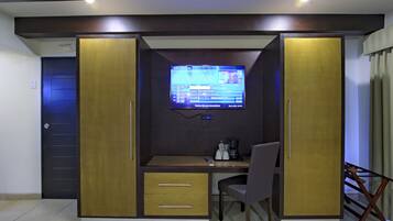 Quarto com cama, escrivaninha e televisão.