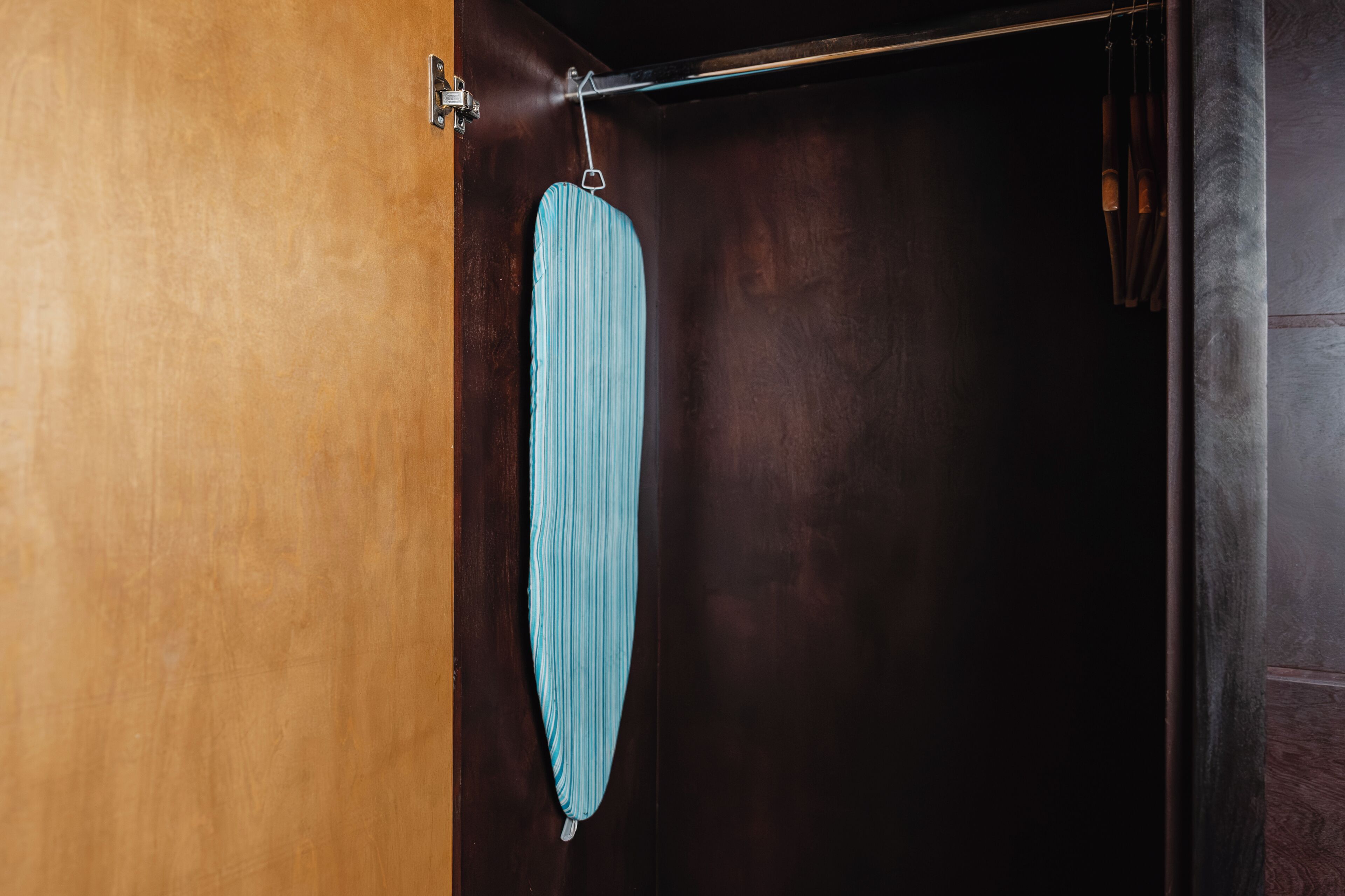 Una habitación con puerta de madera, toalla colgada y pared oscura.