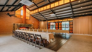 A spacious hall with a long table set for a meal, a brick wall, and a fireplace. - Hotel La Pinta (Ensenada)