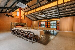 A spacious hall with a long table set for a meal, a brick wall, and a fireplace.