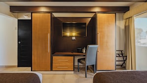 A bedroom with a bed, a desk with a chair, a TV, and a wardrobe. - Hotel La Pinta (Ensenada)