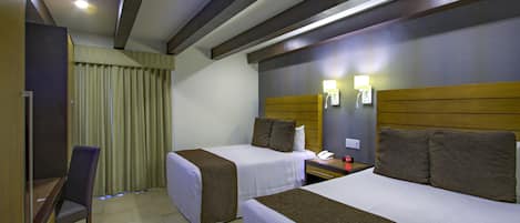 Habitación de hotel con dos camas, un escritorio y una silla.
