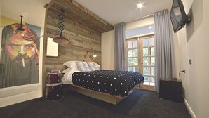 Un dormitorio con cama, una pared decorativa de madera, una ventana con cortinas y un televisor montado en la pared.