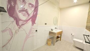 A bathroom with a tiled wall, a wooden vanity, a mirror, and a white toilet.