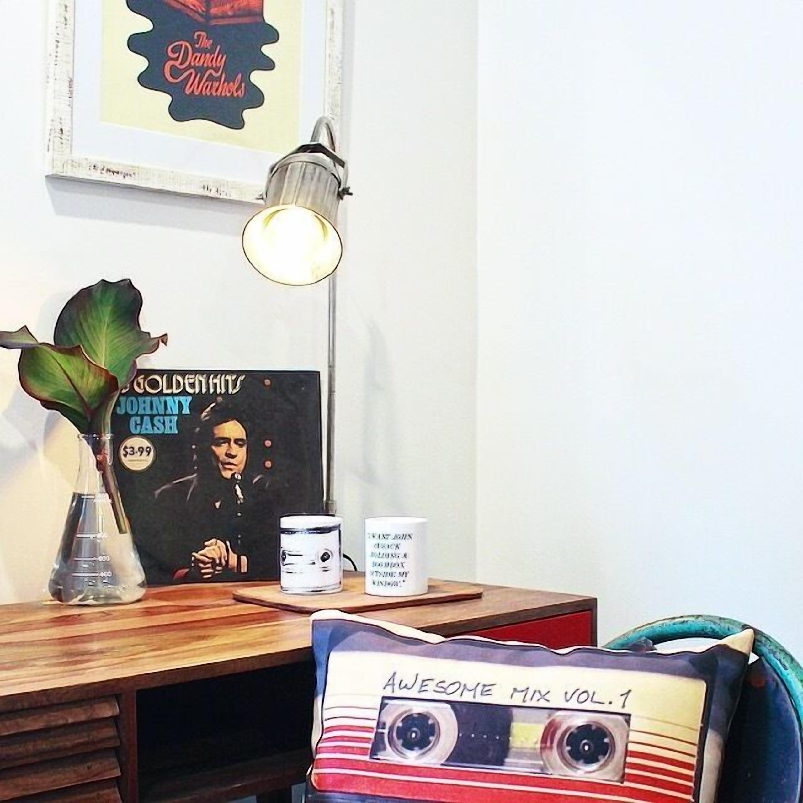 A desk with a vinyl record, a lamp, a plant, and a framed poster.