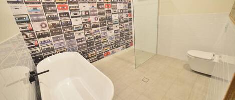 A bathroom with a white bathtub, a glass shower enclosure, and a toilet.