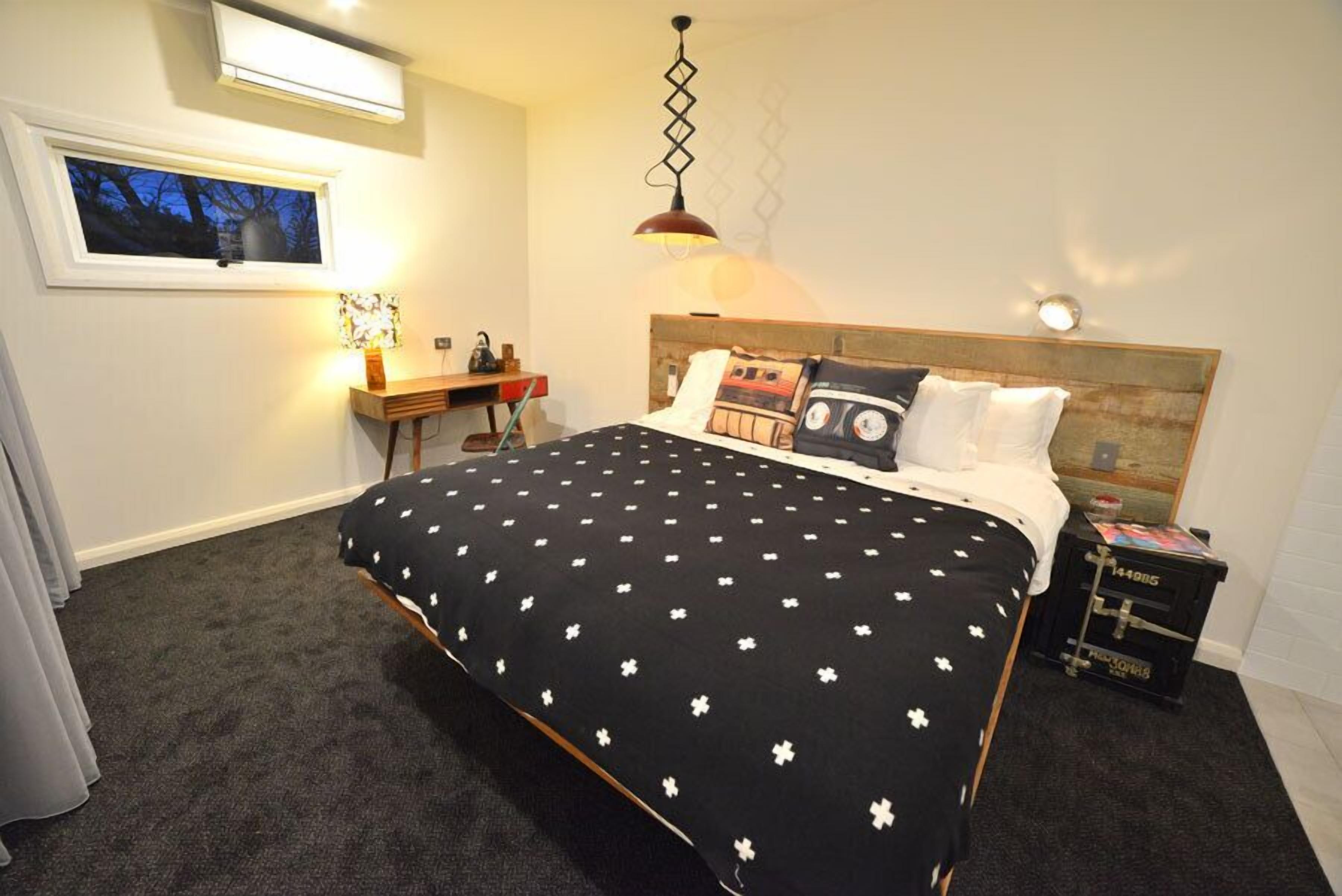 Une chambre à coucher avec un lit, un bureau, une lampe et une fenêtre.