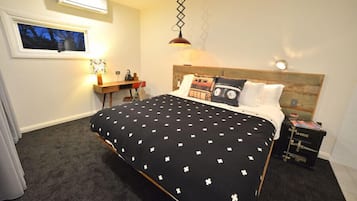 A bedroom with a bed, a desk, a lamp, and a window.