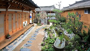 A traditional Japanese garden with stone paths, a koi pond, and wooden buildings. - Happiness Full Guesthouse (Jeonju)