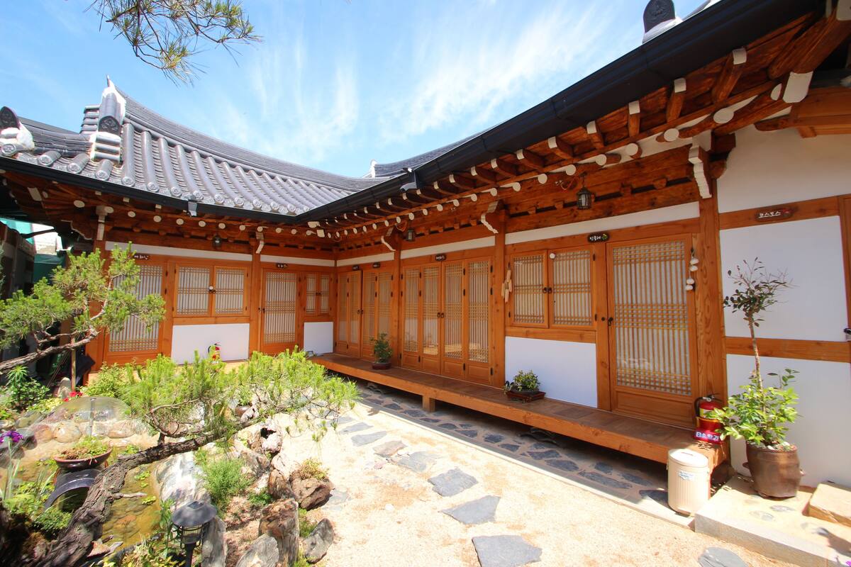 Ein traditionelles japanisches Gebäude mit Holzarchitektur, einem Steinweg und Kübelpflanzen.