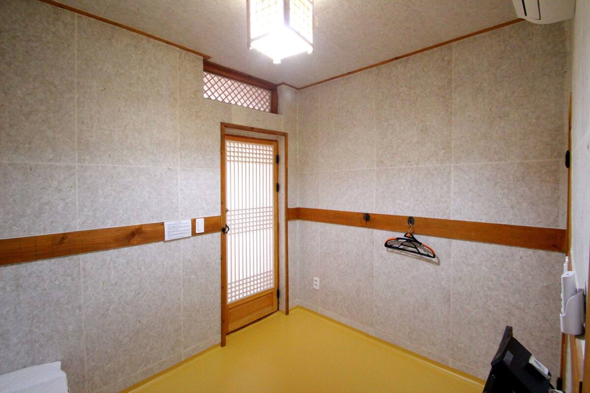 Ein Zimmer mit Holztür, gelbem Boden und einem an der Wand befestigten Ablagefach.