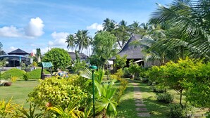 A tropical resort with thatched-roof huts, lush greenery, and a clear sky.