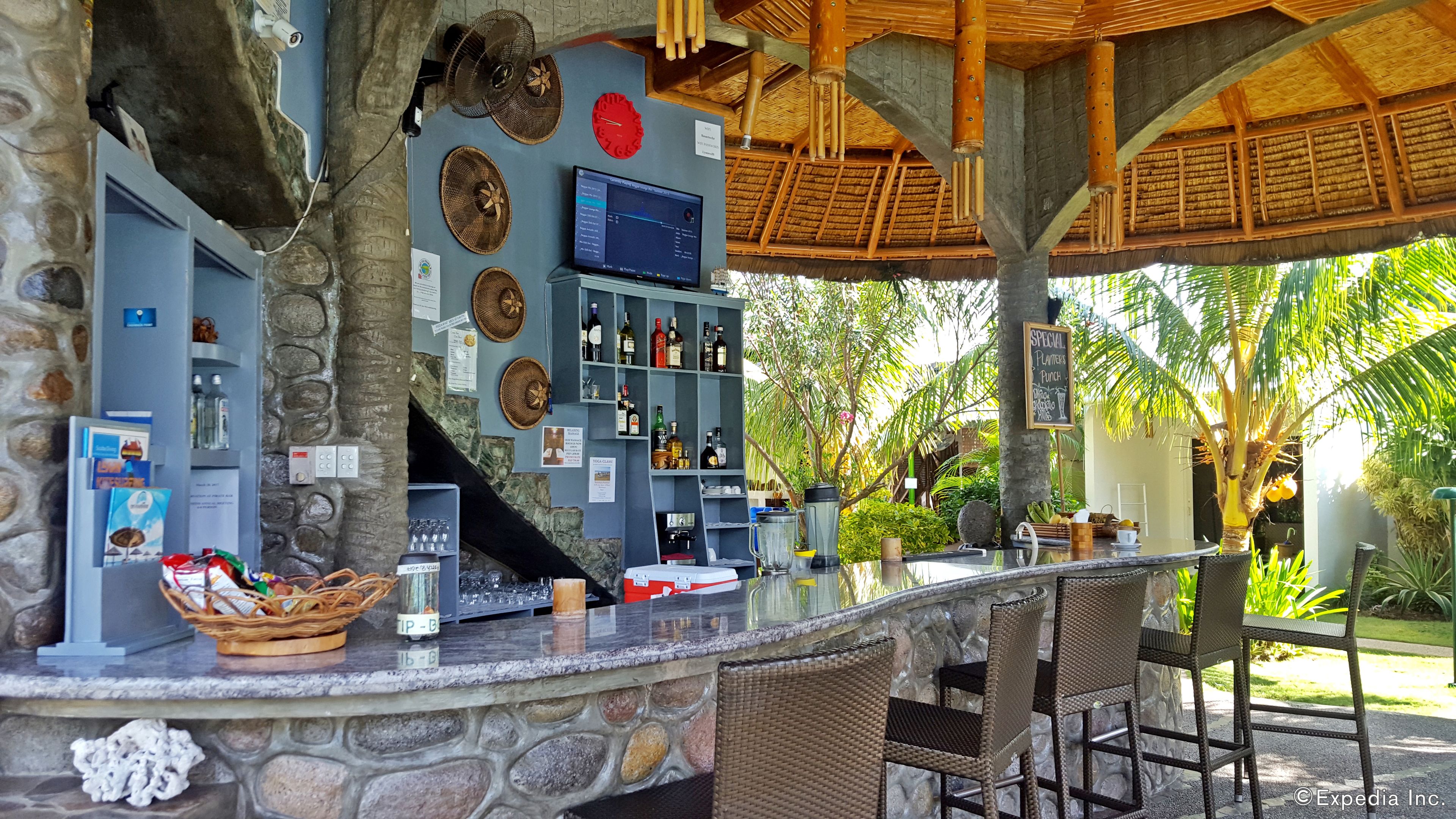 A bar area with a stone counter, wicker chairs, and a thatched roof.