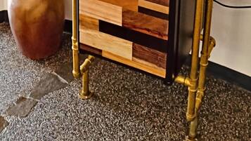 A minibar with a wooden top, brass pipes, and a black control panel.