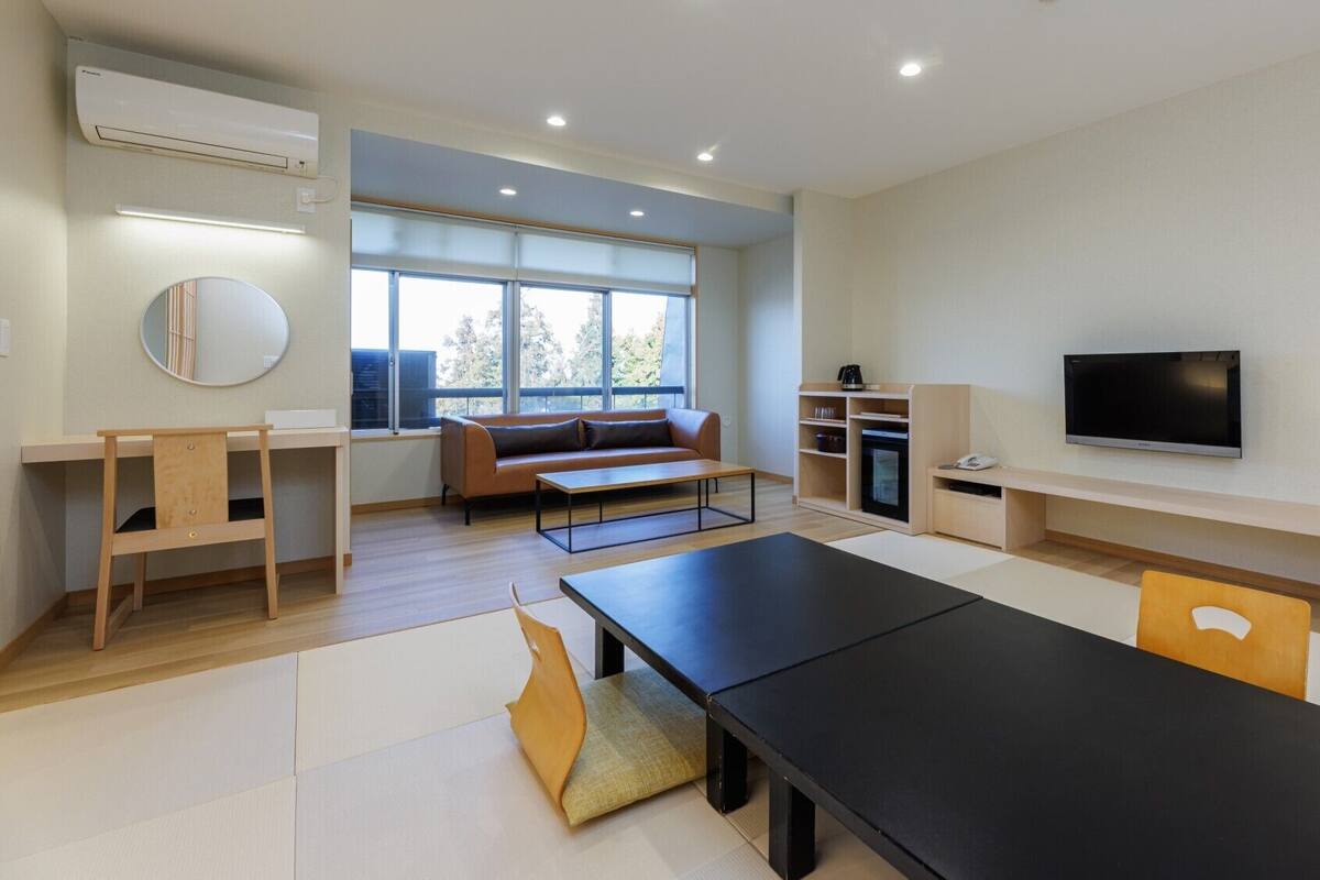 A modern living room with a sofa, TV, and a dining table.