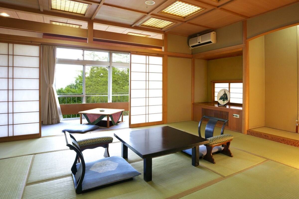 A traditional Japanese room with tatami flooring, a low table, a cushioned chair, and sliding shoji doors.