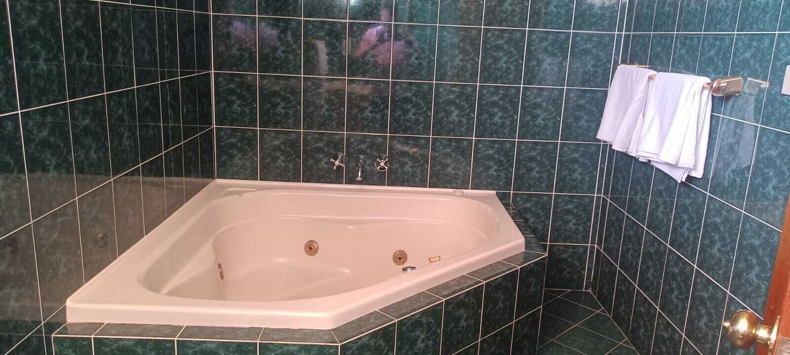 A rectangular bathtub in a bathroom with dark green marble tiles.