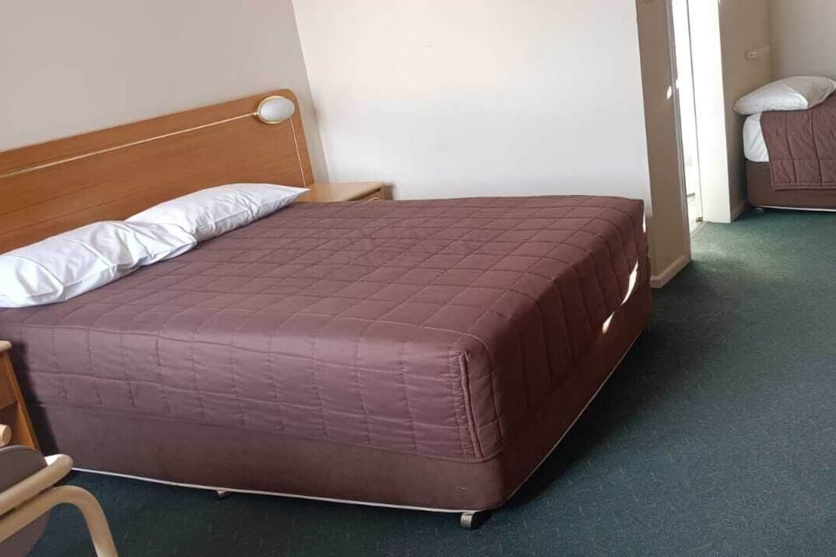 A room with two beds, a wooden headboard, a small table, and a chair.
