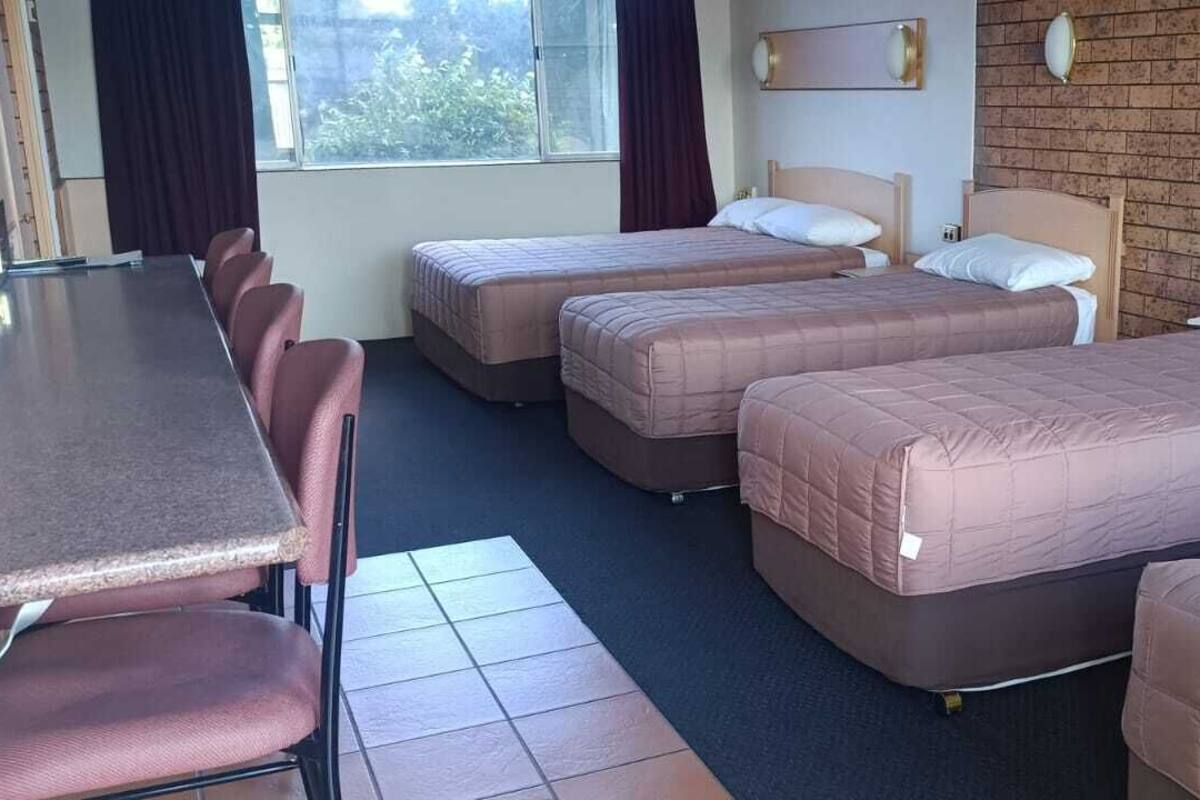 A hotel room with four beds, a dining table, and chairs.