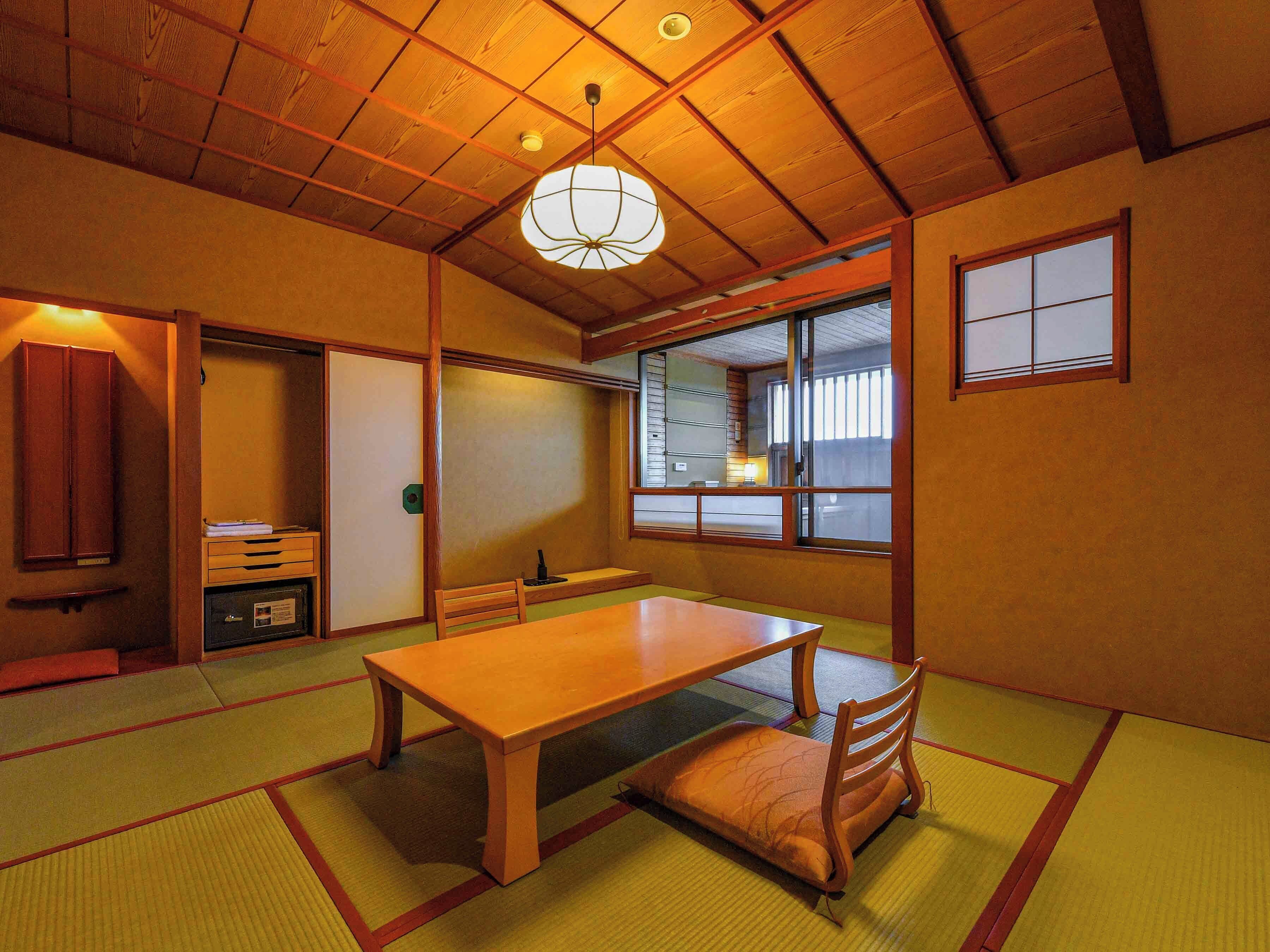 A traditional Japanese room with tatami flooring, a wooden table, a low wooden bench, and a sliding door.