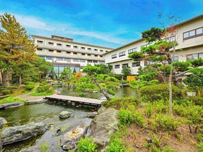 A traditional Japanese garden with a koi pond, surrounded by well-maintained greenery and a wooden bridge. - Hokuriku Fukui Awara Onsen Mimatsu (Awara)