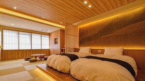A spacious bedroom with a large bed, wooden flooring, tatami mats, a wooden headboard, and a sliding shoji screen. - Hokuriku Fukui Awara Onsen Mimatsu (Awara)