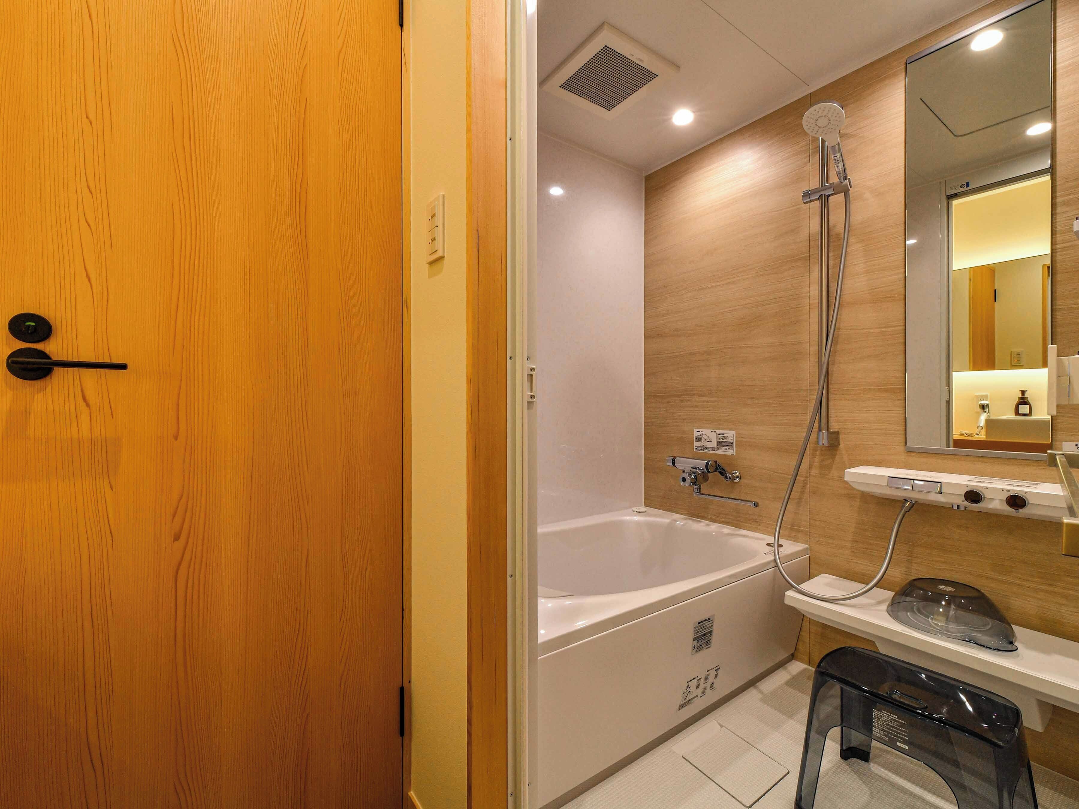 Un baño moderno con puerta de madera, bañera, ducha y espejo sobre el lavamanos.