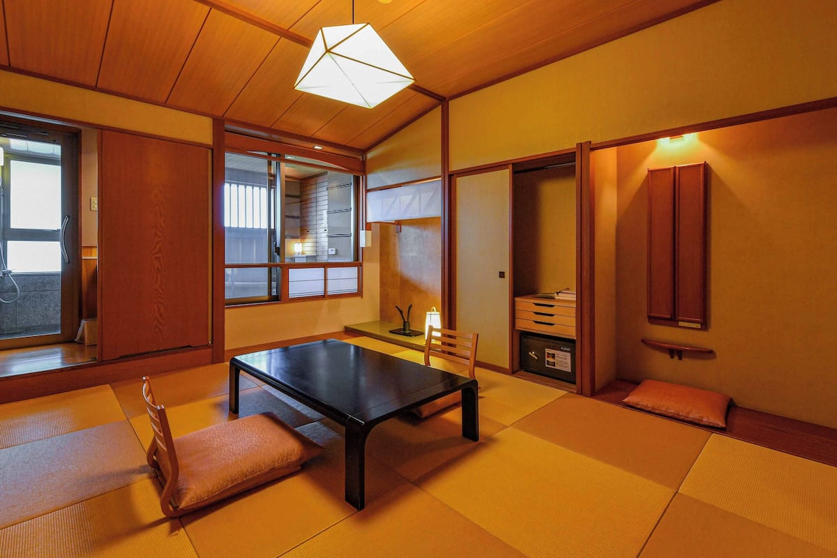 A traditional Japanese room with tatami flooring, a low table, a chair, and sliding doors.