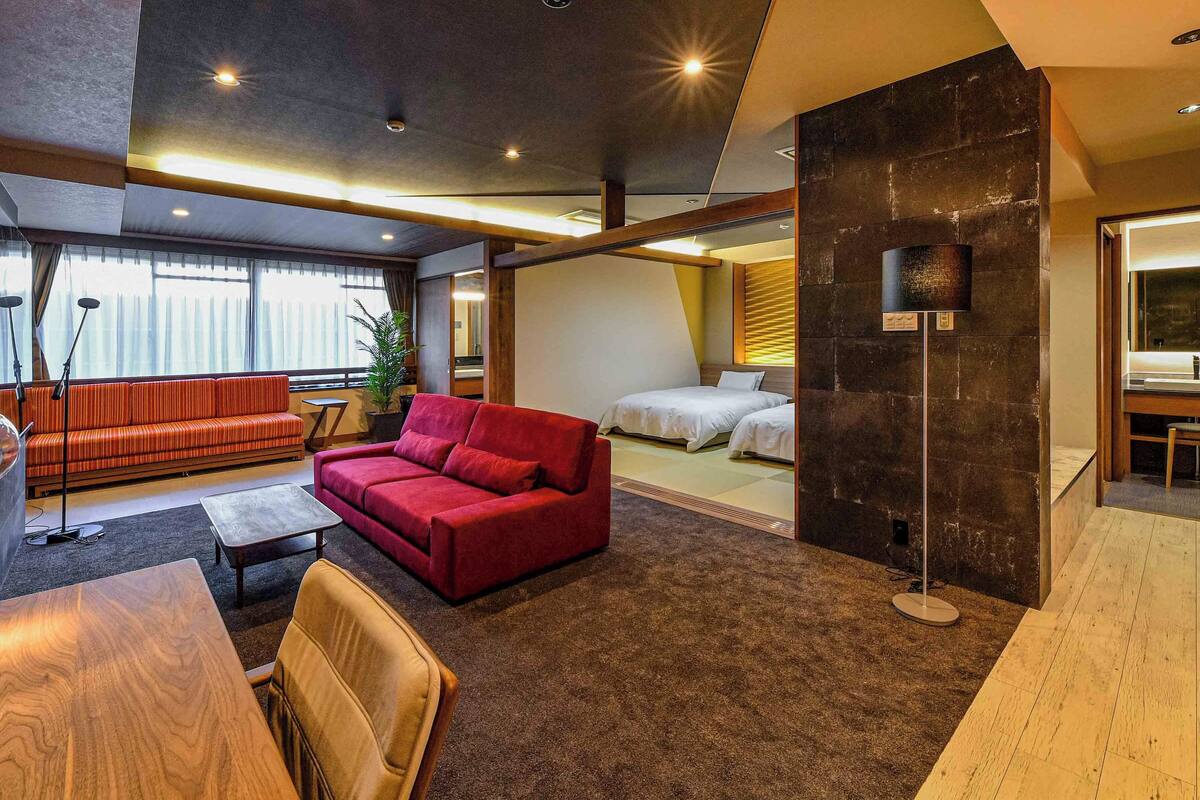 A modern living room with a red sofa, a wooden coffee table, and a large mirror.