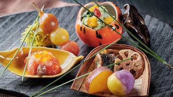 A variety of food items on a slate board, including a dish with grapes, a bowl with a fruit salad, and a plate with a piece of meat.