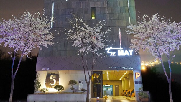 A tall building with a 'MAY' sign at the top and a '5' sign at the entrance. - Hotel The May (Gwangju)
